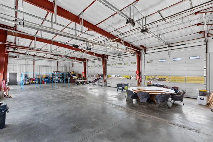 Expansive open-concept industrial space featuring a concrete floor, exposed red structural beams, and white insulated ceilings