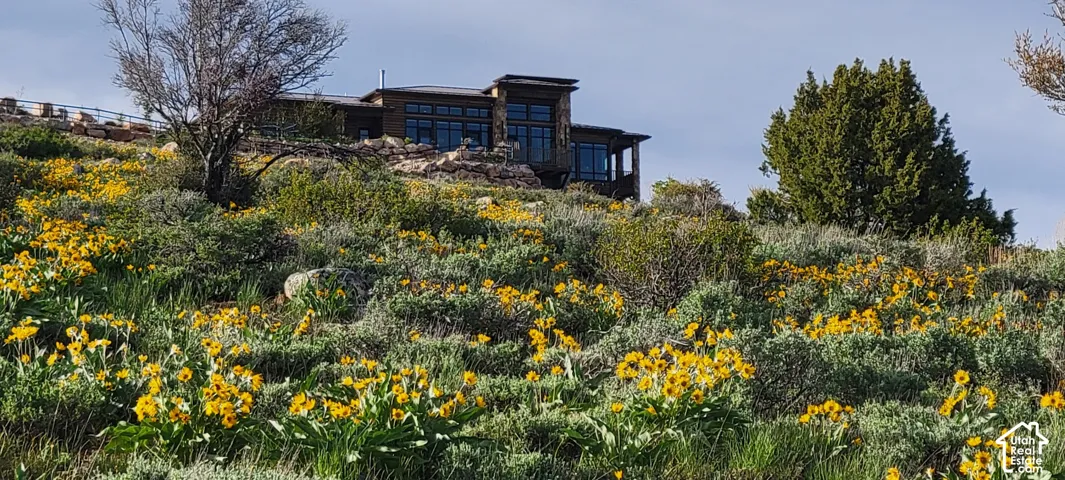 Hillside property featuring a multi-level design, extensive windows, a stone exterior, and a prominent balcony