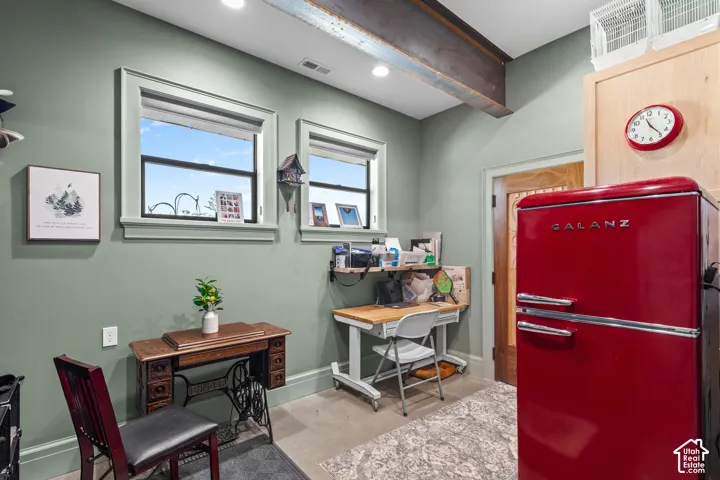 Exposed steel beam ceiling accenting a room with two windows, light green walls, and concrete flooring