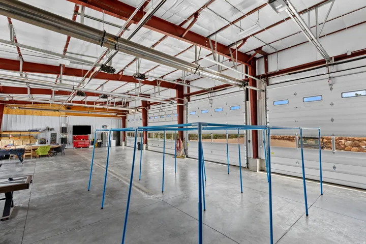 Expansive commercial bay featuring a polished concrete floor, red I-beam construction, and multiple overhead doors with integrated windows
