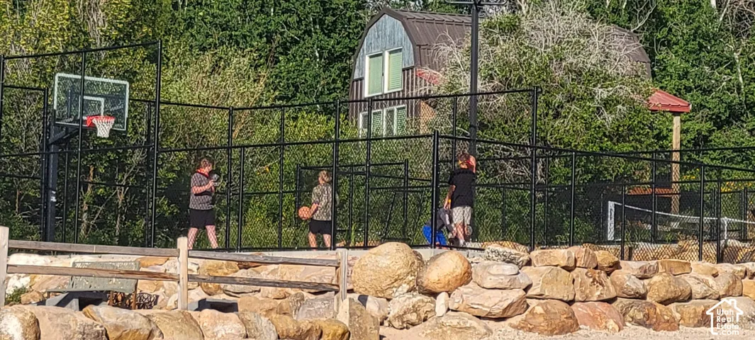 Enclosed sports court featuring a basketball hoop and a paddleball net