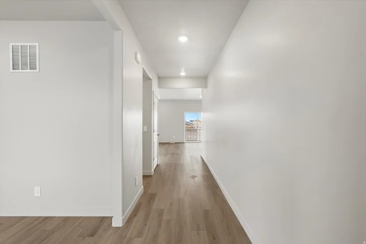 Hallway featuring wood-finish flooring, recessed lighting, and a neutral color palette