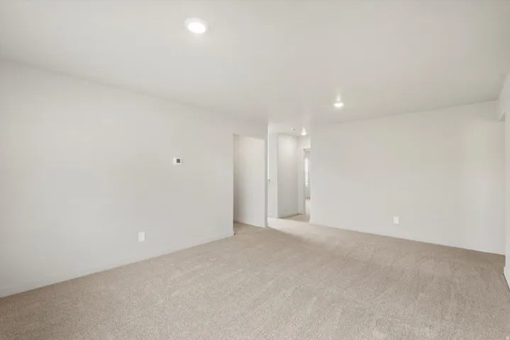 Spacious room featuring light neutral wall paint, recessed ceiling lighting, and soft pile carpeting