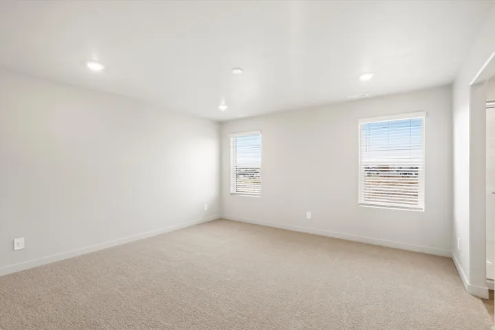 Spacious room featuring neutral carpeting, light-toned walls, and recessed lighting