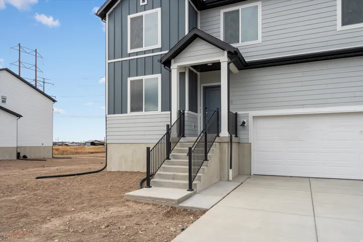 **DISCLAIMER** Exterior elevation may vary. Contemporary exterior with horizontal and vertical siding, concrete steps with black railings, a covered entryway with a gray door, and an attached garage with a white door