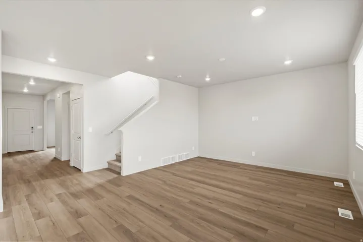Spacious interior featuring wood-finish flooring, recessed lighting, neutral paint, and a carpeted staircase
