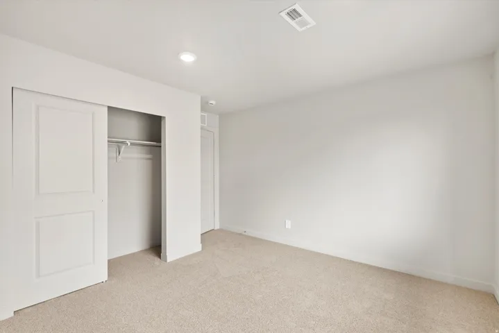 Carpeted room with a sliding door closet featuring a built-in rod and shelving