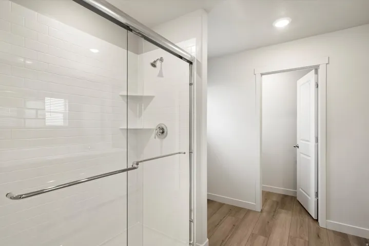 Shower with subway tile surround, integrated shelving, and sliding glass enclosure