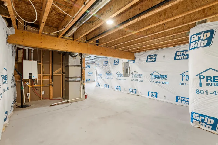 Unfinished basement with exposed wood joists and subflooring, insulated walls, and concrete flooring