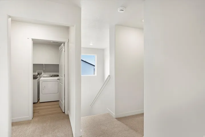 Dedicated laundry area with light wood-finish flooring, built-in shelving, and white walls