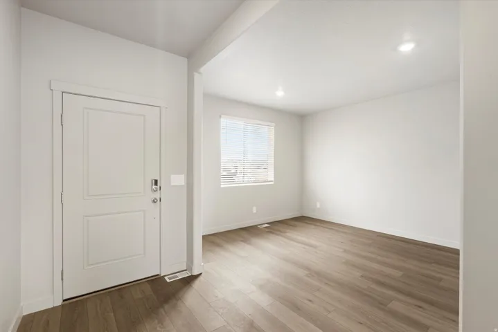 Entryway featuring a paneled door with smart lock hardware, wood-finish flooring, recessed lighting, a window with blinds, and white baseboards