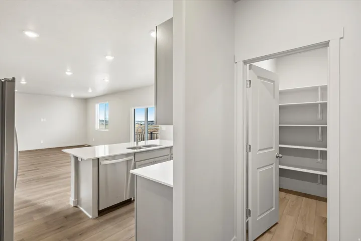 Kitchen featuring a stainless steel refrigerator, white countertops, built-in dishwasher, and recessed lighting