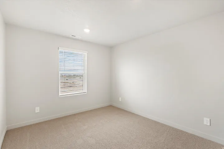 Neutral tone painted walls with a single window featuring horizontal blinds