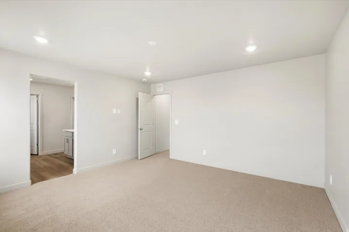 Bright room featuring neutral carpeting, recessed lighting, and crisp white walls