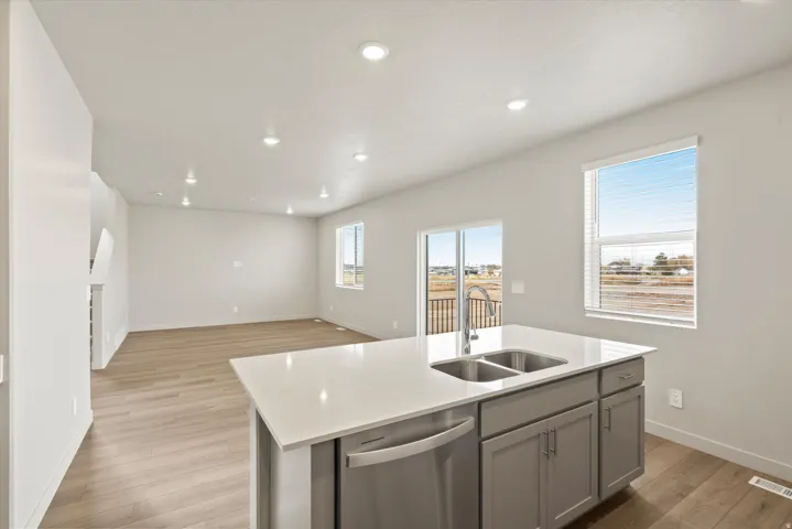 Kitchen island featuring a double-basin stainless steel sink, gooseneck faucet, and light-toned solid surface countertop