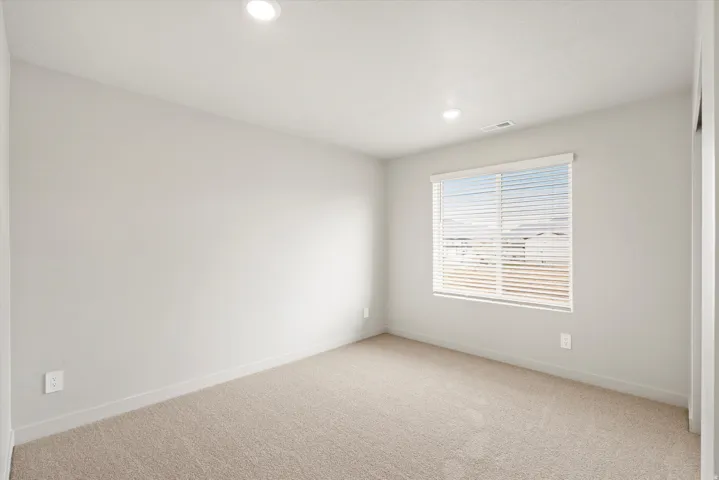 Bright room featuring neutral-toned walls, recessed lighting, and a single window with horizontal blinds