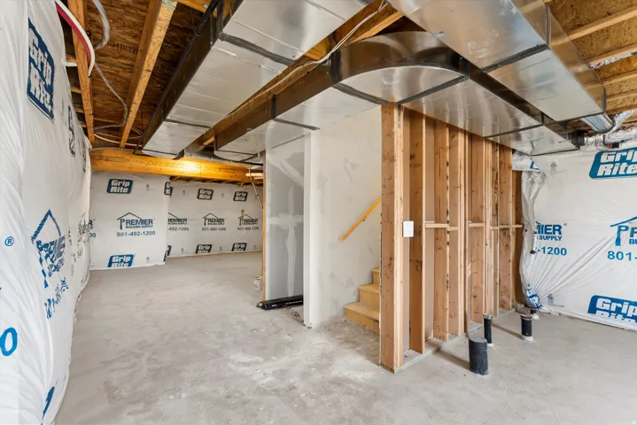 Unfinished basement with exposed ceiling joists, visible ductwork, and concrete flooring