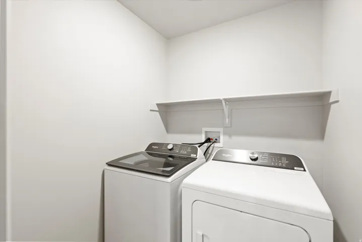 Dedicated laundry area featuring a white floating shelf, white walls, and a ceiling-mounted light fixture