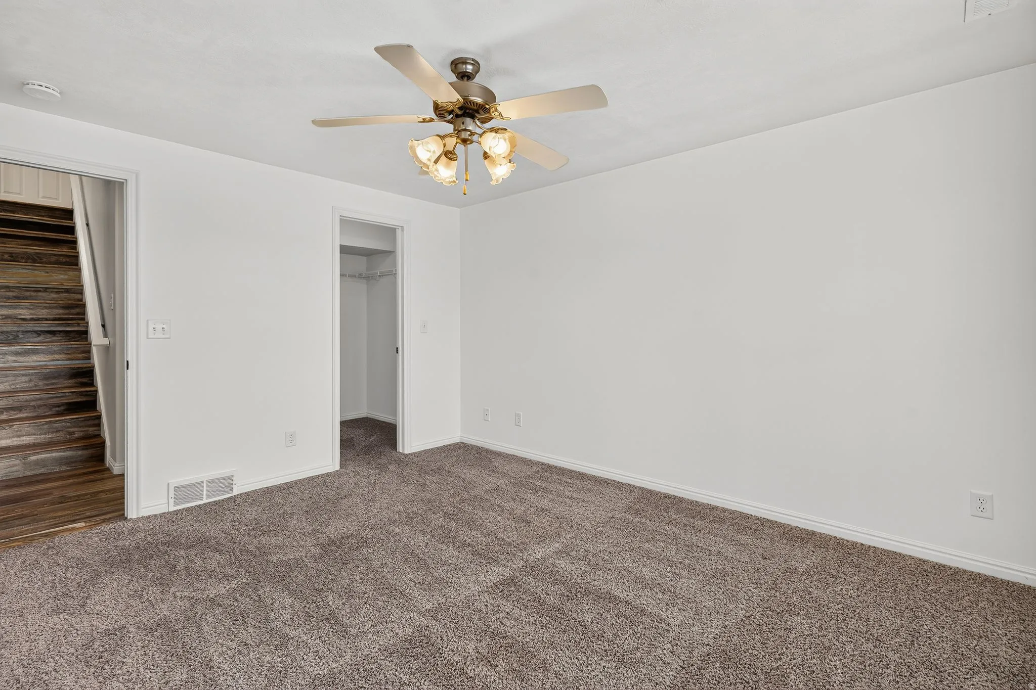 Carpeted room with white walls, featuring a ceiling fan with integrated lighting