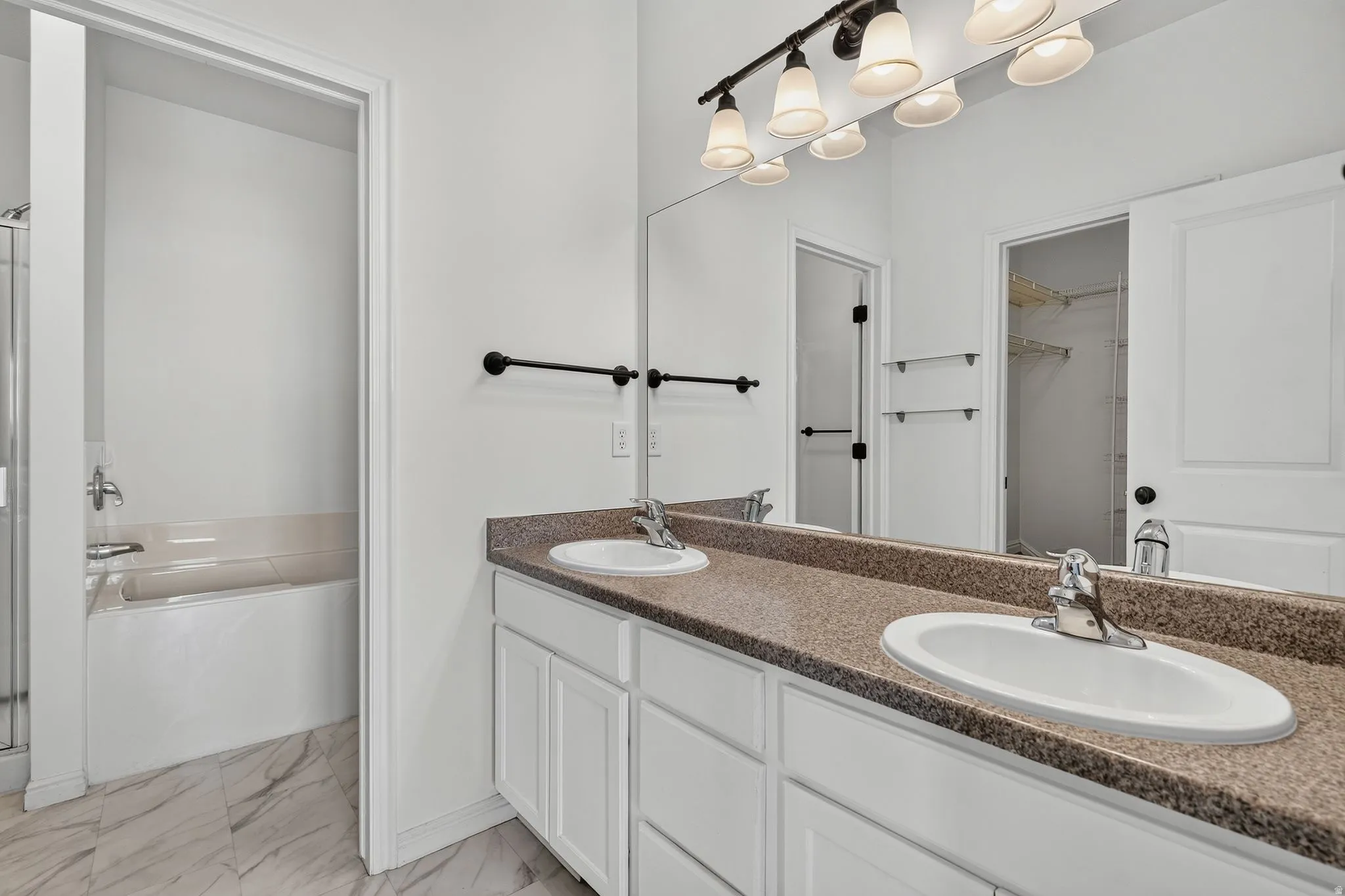 Dual vanity featuring white cabinetry, a speckled countertop, and chrome fixtures