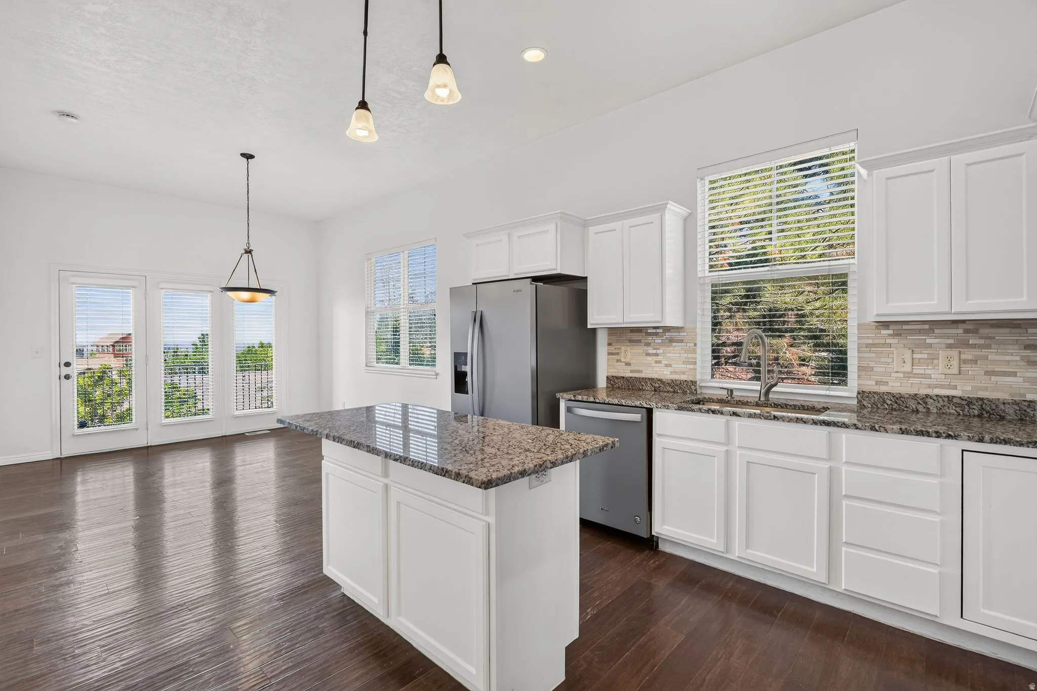 Kitchen featuring white shaker cabinetry, stainless steel appliances, granite countertops, and a tile backsplash