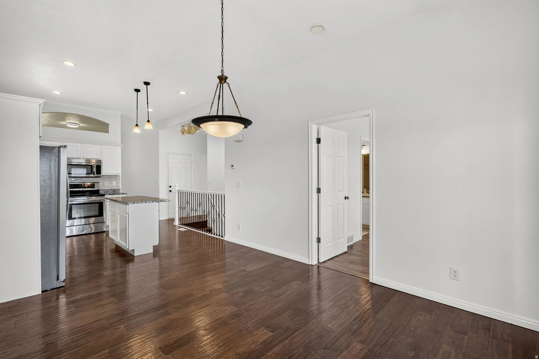 Open-concept living area featuring rich wood-finish flooring, recessed lighting, and a kitchen with stainless steel appliances