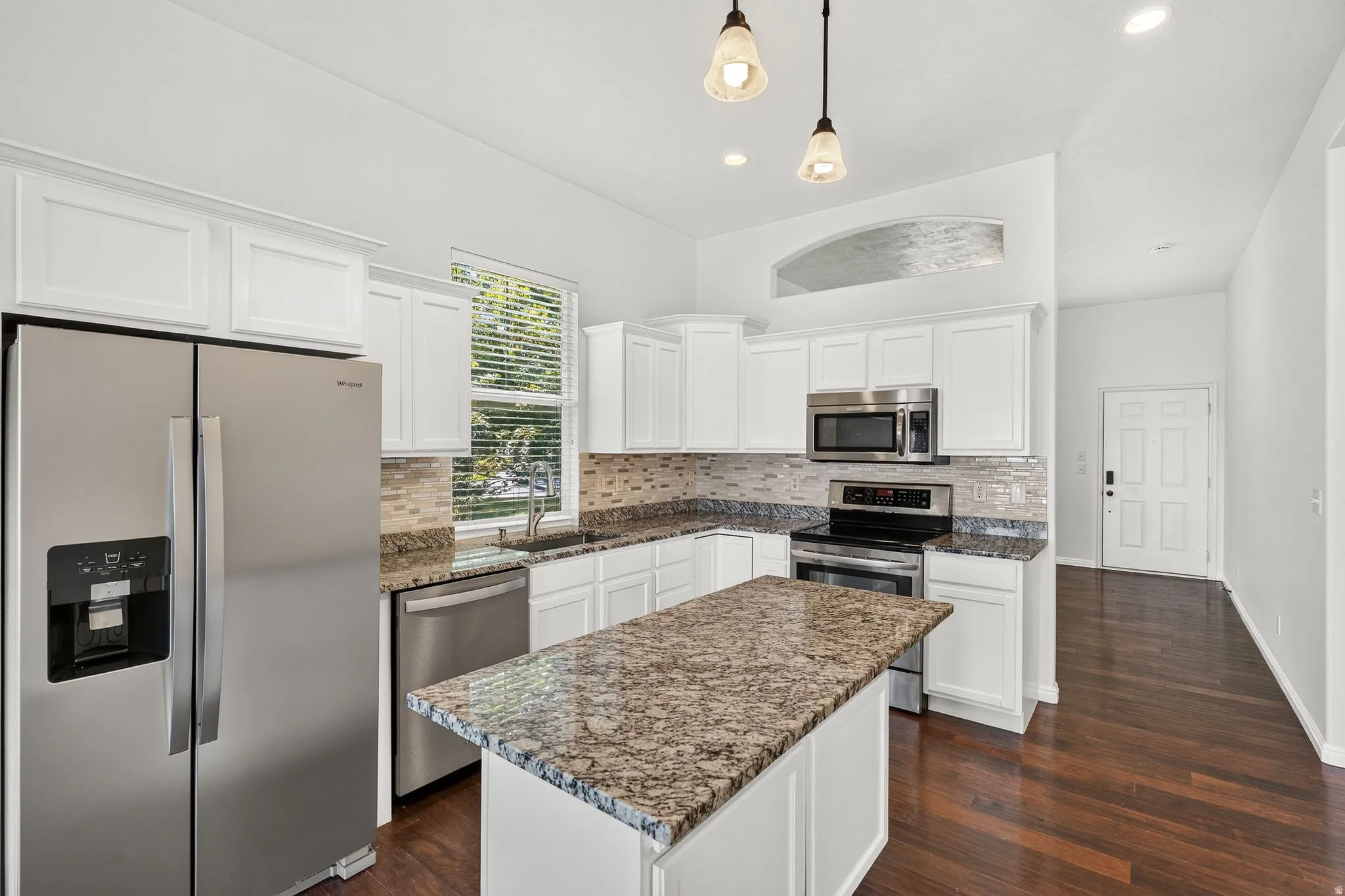 Modern kitchen featuring white cabinetry, stainless steel appliances, and wood-finish flooring