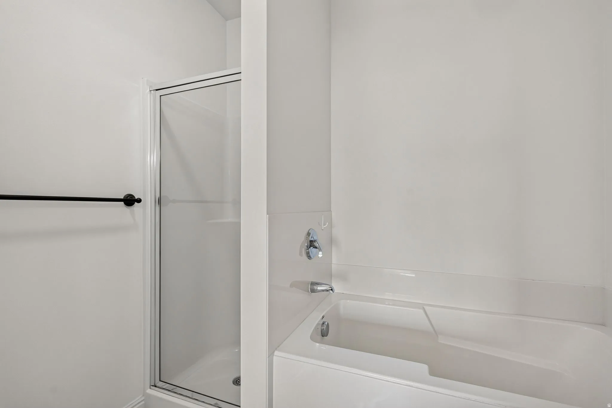 Bathroom featuring a white bathtub, chrome fixtures, and an enclosed shower with a glass door