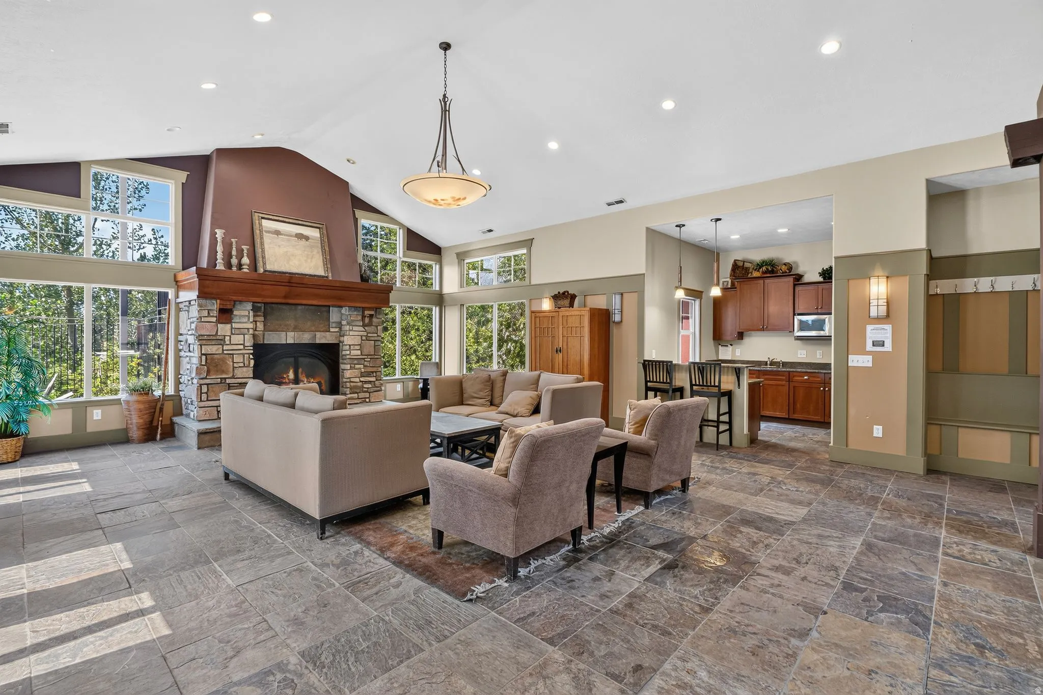 Great room featuring a prominent stone fireplace with a wood mantle, vaulted ceilings, and extensive window walls