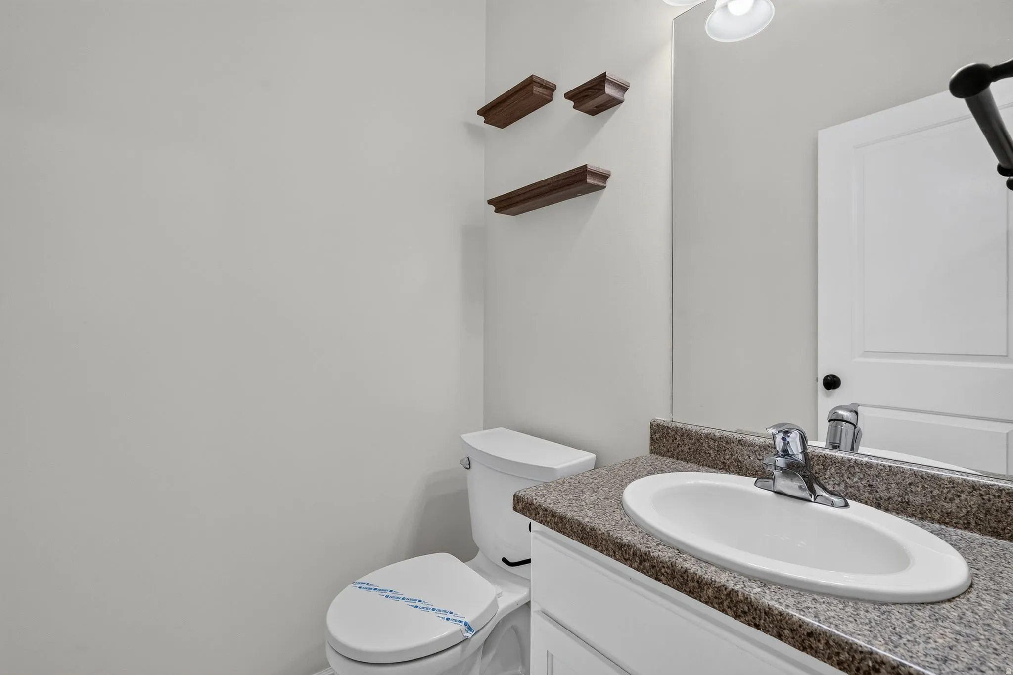 Bathroom featuring a vanity with a speckled countertop, an undermount sink, and a chrome faucet