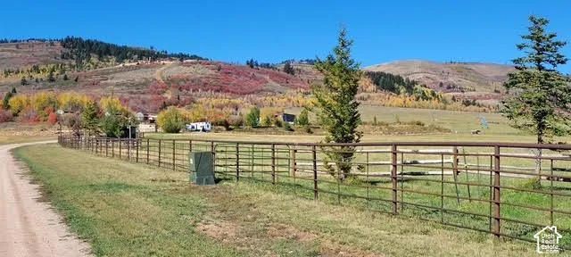 Expansive fenced property with a gravel drive and surrounding natural landscape