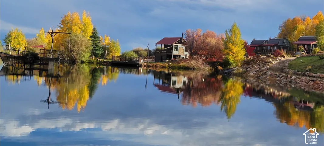 Waterfront property with multiple structures, surrounded by mature trees, and a developed shoreline
