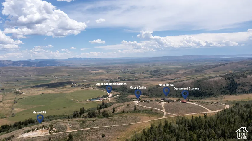 Aerial perspective showcasing multiple structures including a main home, guest cabin, guest accommodations, and equipment storage within a expansive landscape