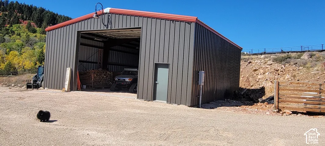Metal-clad structure with a red roof, featuring a large open bay and a separate entry door