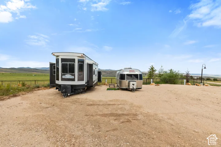 Gravel parking area featuring two recreational vehicles, a contemporary fifth-wheel trailer, and a classic Airstream trailer, RV Hookups