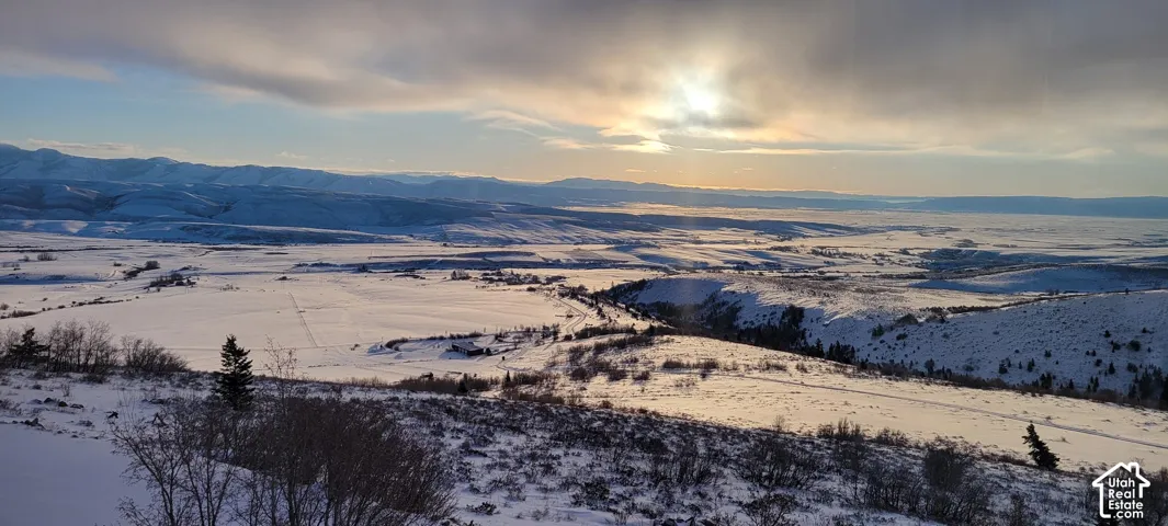 Expansive snow-covered landscape with distant mountains under a dramatic sky
