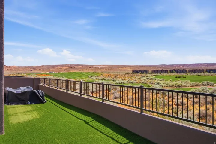 Terrace featuring artificial turf flooring and a dark metal railing