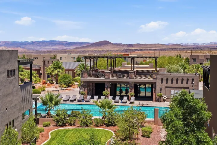 Outdoor pool and lounge area featuring a pergola-covered upper deck, a ground-level patio with sun loungers, perimeter fencing, and surrounding landscaping
