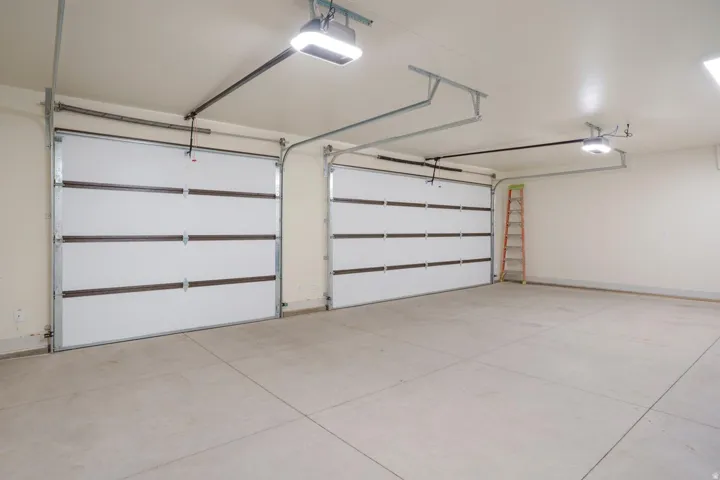 Spacious two-car garage featuring segmented white doors and concrete flooring