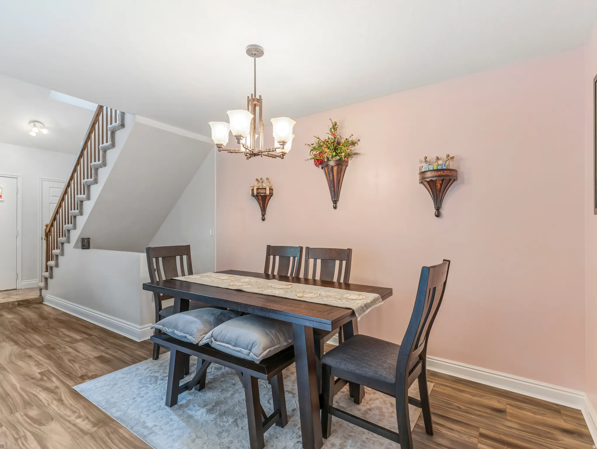 Dining area featuring wood-finish flooring, a contemporary chandelier, and a staircase with wood railings
