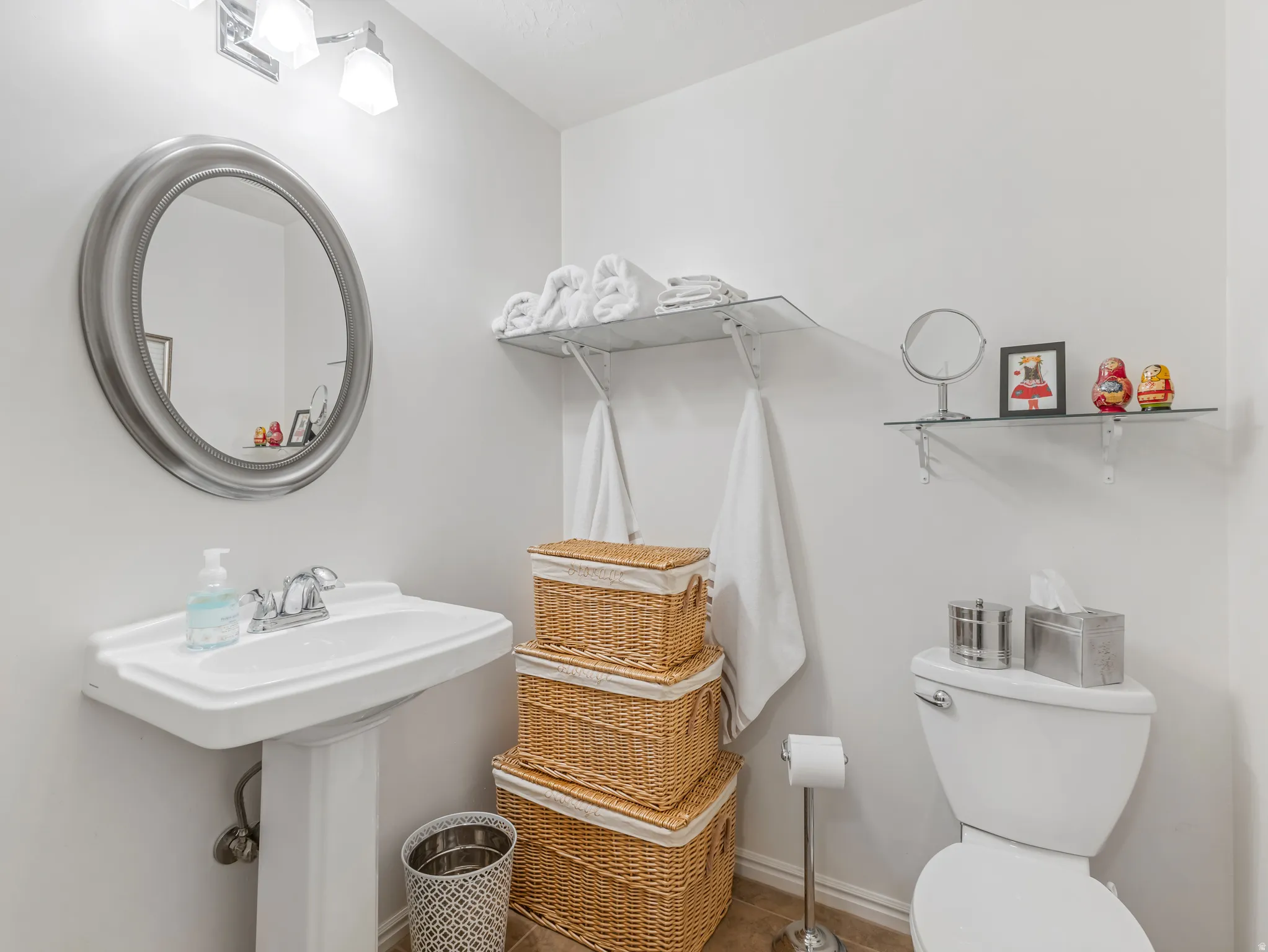 Pedestal sink with chrome faucet, complemented by a large oval mirror
