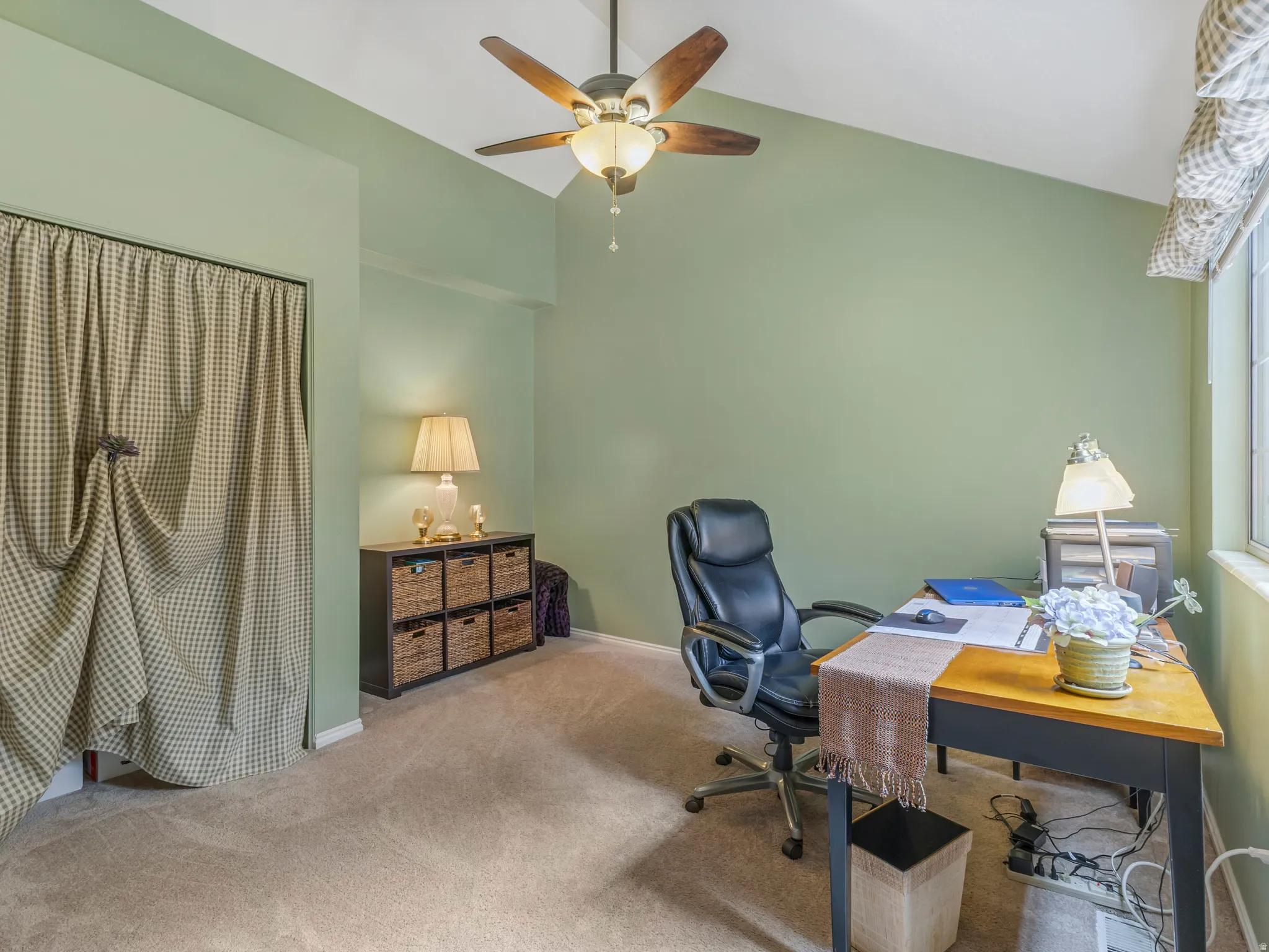 Vaulted ceiling featuring a ceiling fan with integrated lighting, soft green wall color, and carpet flooring