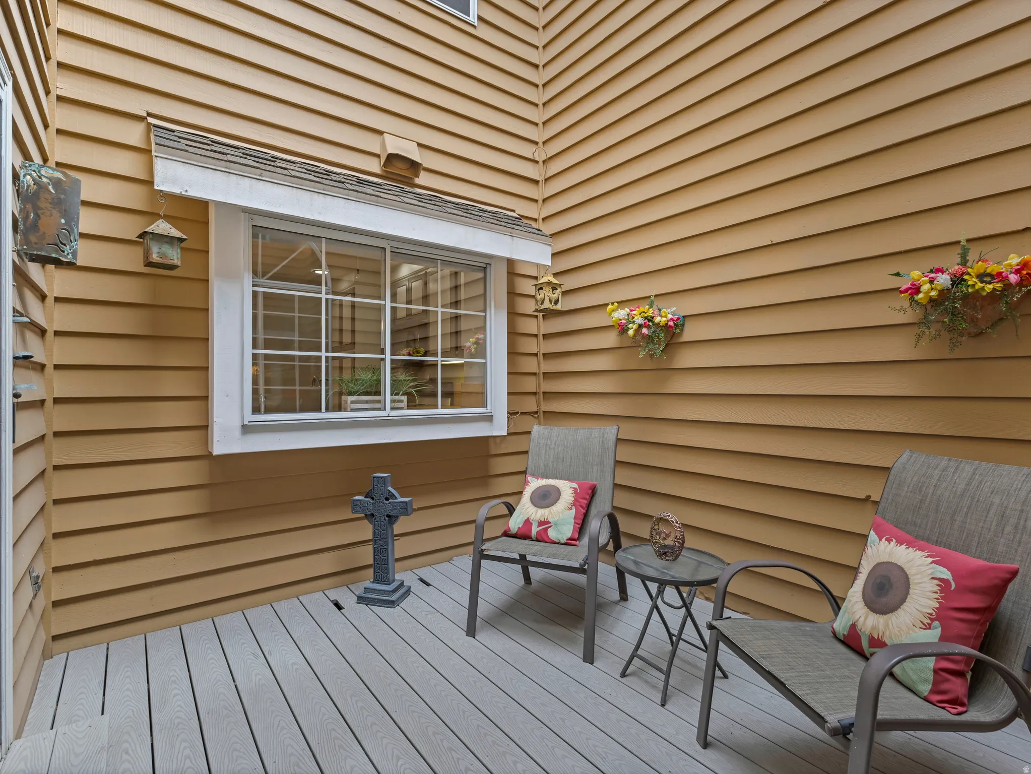 Exterior patio featuring composite decking, horizontal siding, and an awning-style window