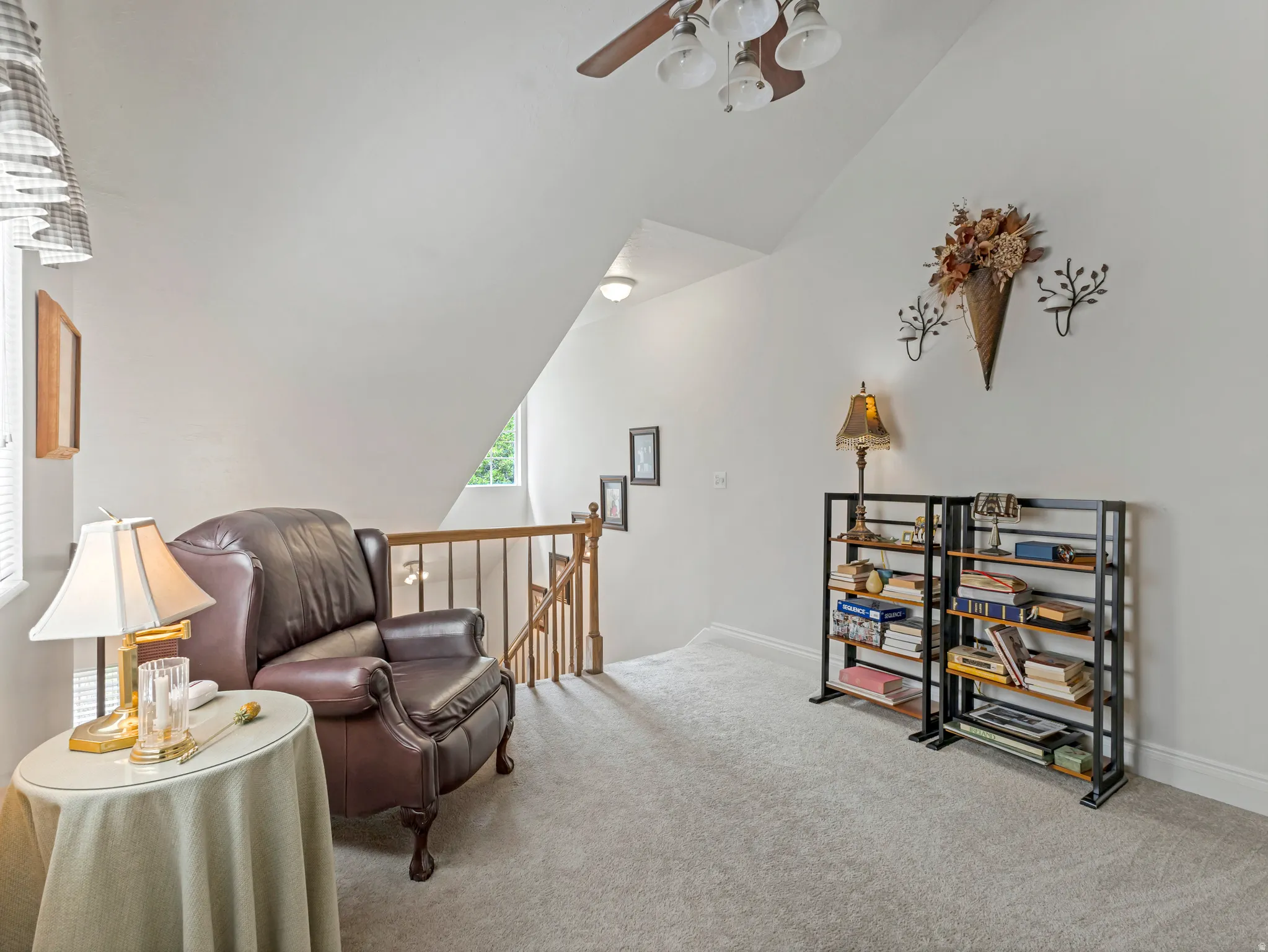 Carpeted loft area featuring a sloped ceiling and natural wood railing