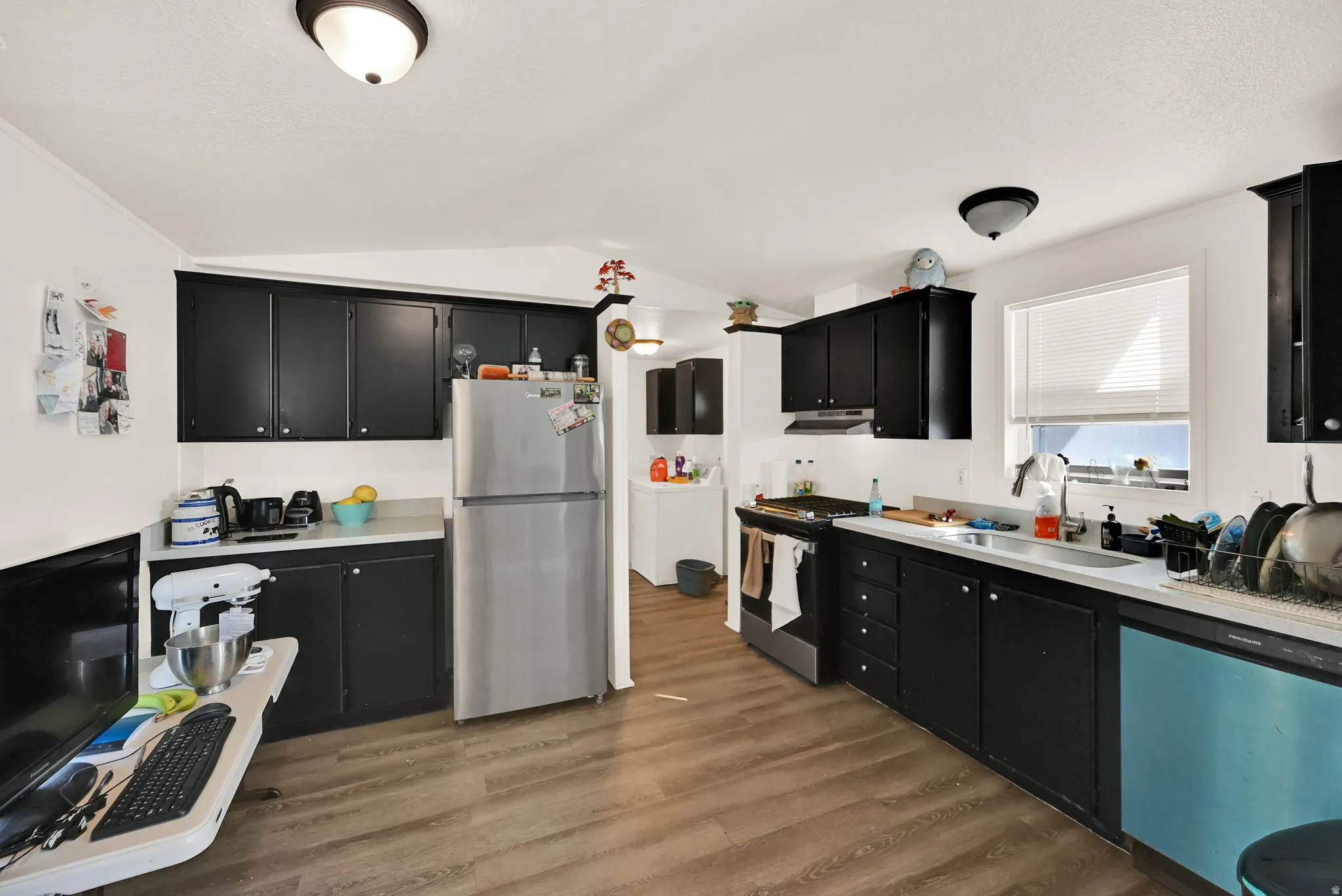 Kitchen featuring wood-finish flooring, black cabinetry, and light-toned countertops