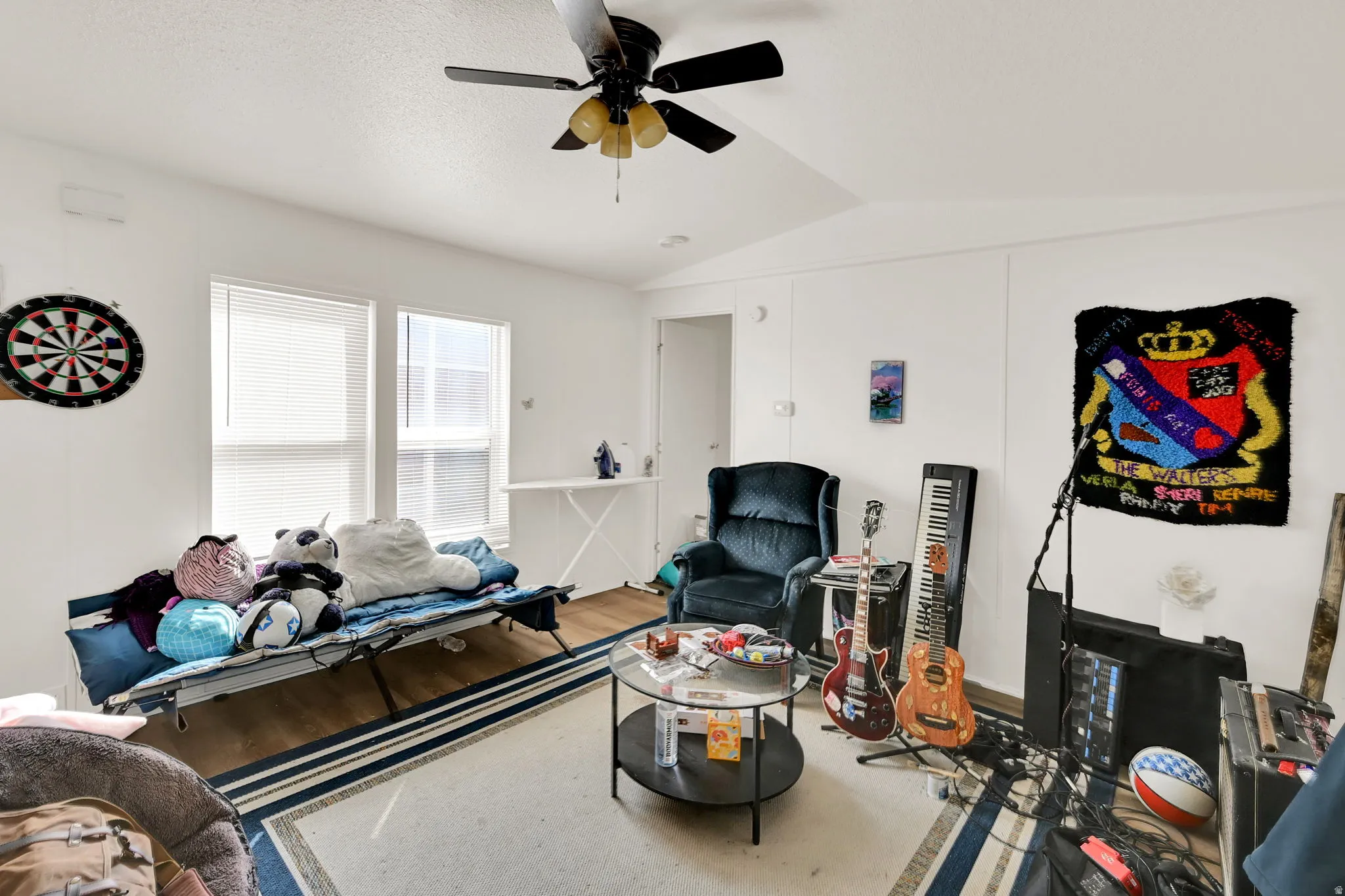 Bright interior room featuring white walls, multiple windows with blinds, and wood-finish flooring