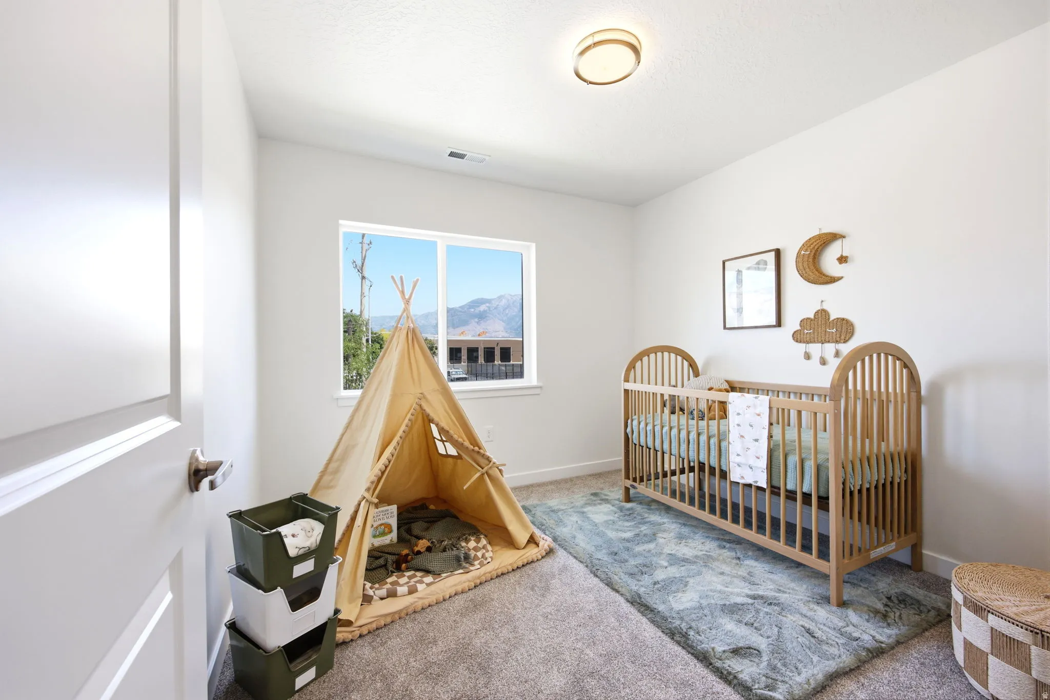 Neutral-toned room featuring a window with a mountain backdrop, plush carpet flooring, white walls, and a contemporary flush-mount ceiling light