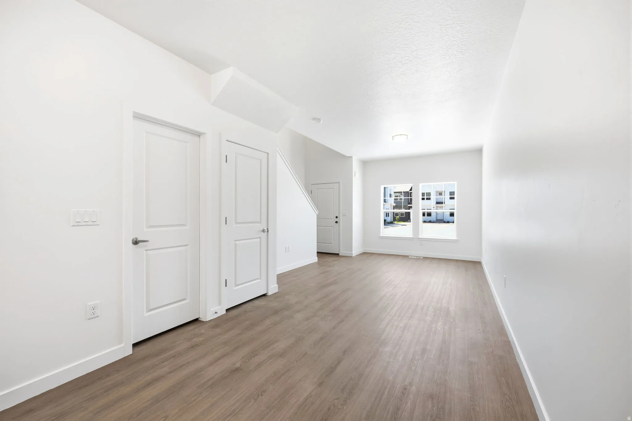 Open-concept interior featuring light wood-finish flooring, white walls, and bright overhead lighting