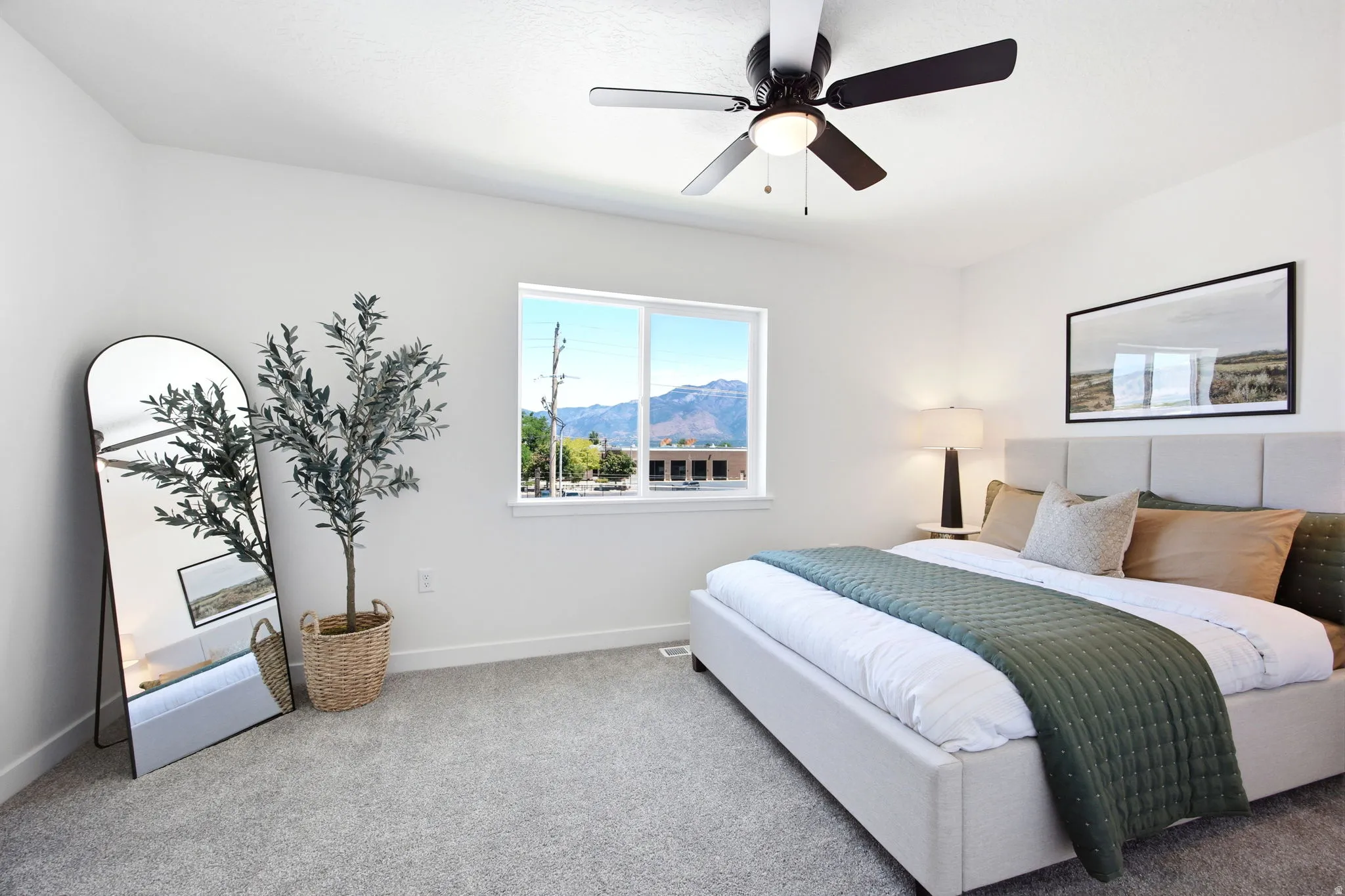 Spacious room featuring a large window, neutral wall tones, textured carpeting, and a ceiling fan with integrated lighting