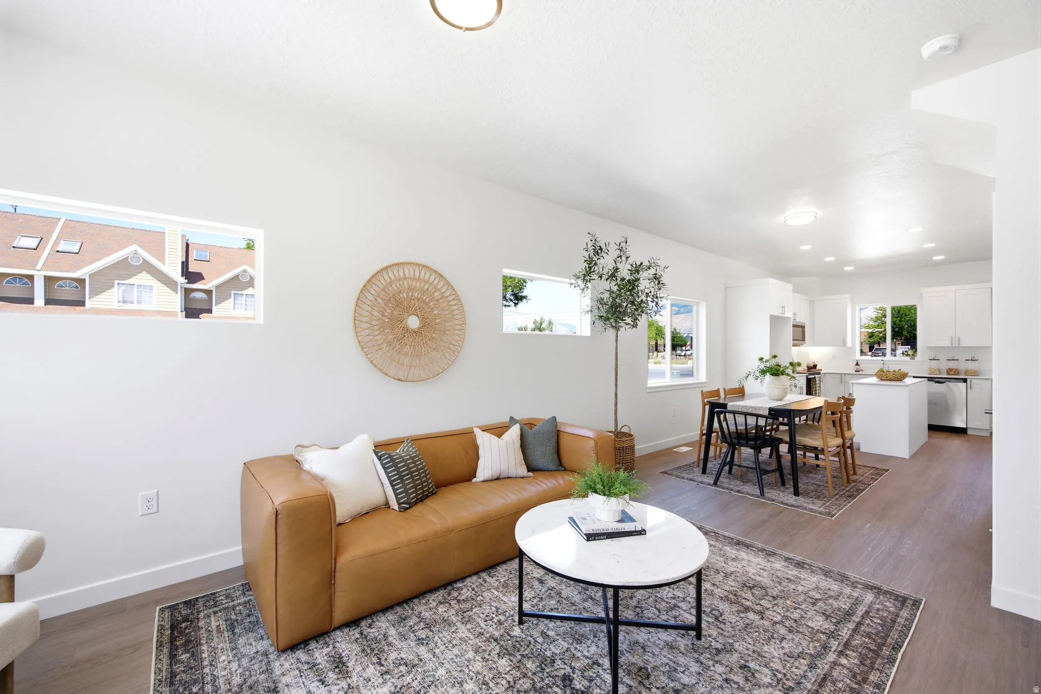 Open-concept living space featuring wood-finish flooring, recessed lighting, and multiple windows